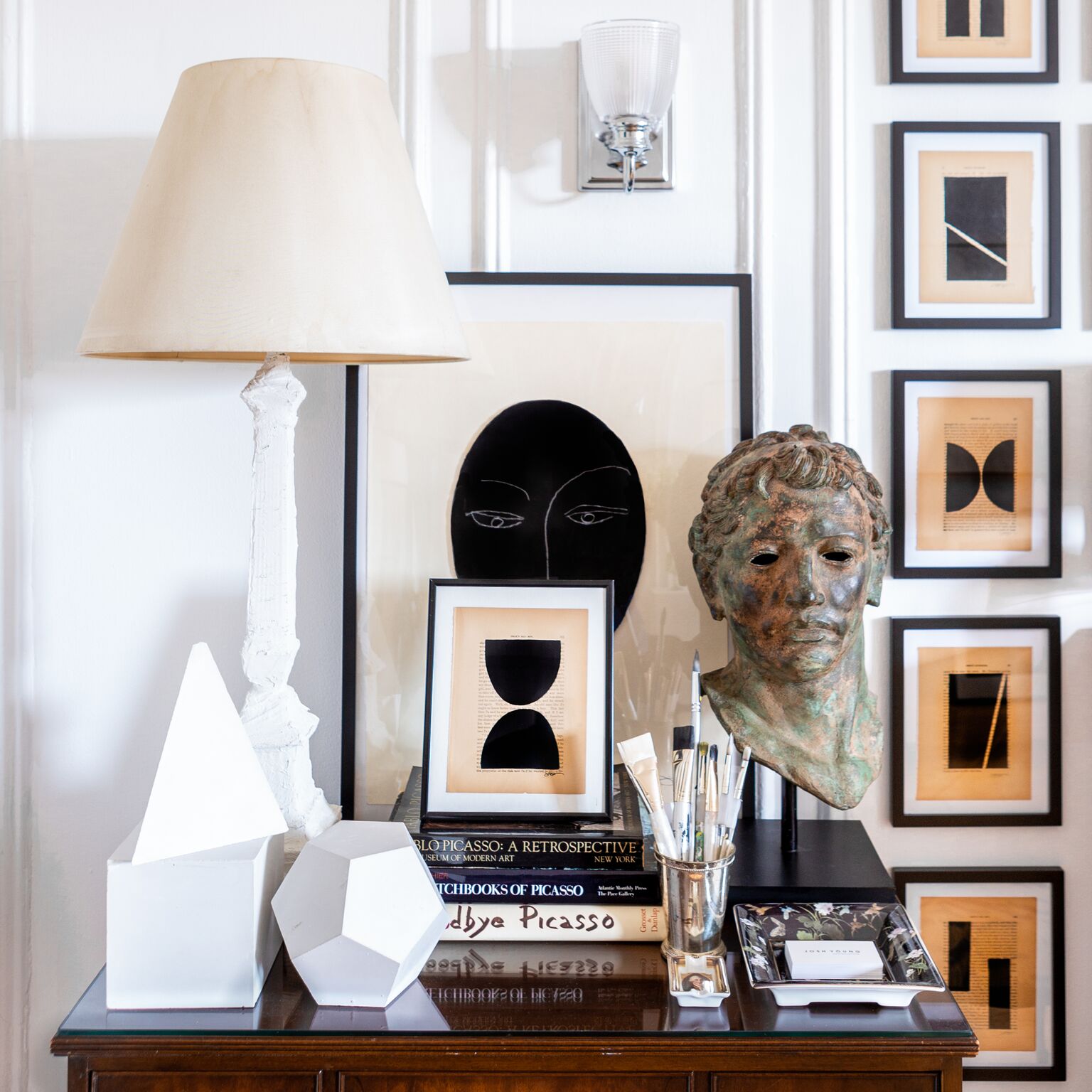 Hidden behind and beneath geometric curios, a hand-plastered lamp, a classical bust, paintbrushes, and his own art is Young’s much-cherished mini library dedicated to Picasso. “It’s a cliché, but I became absolutely obsessed with Picasso in high sch…